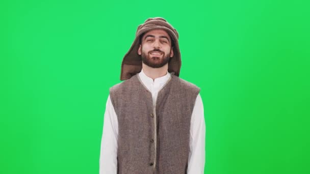 Retrato de um homem alegre de aparência árabe em roupas tradicionais, um homem no fundo de um cromo, câmera lenta. — Vídeo de Stock