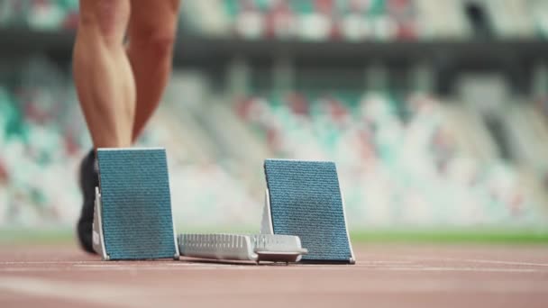 Uomo velocista si prepara per l'inizio di una corsa di allenamento a breve distanza, corridore pista professionale in uno stadio, un momento teso, palmare. — Video Stock