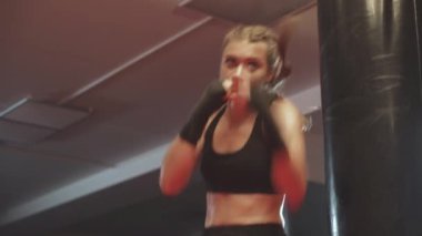 Kadın dövüşçü boks salonunda yumruklarını ve savunmasını eğitir. Kadın dövüşçü, ön tarafta bir dizi yumruk eğitir..