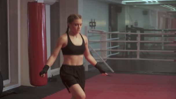 Kadın boksör trenleri ve ip atlama, koordinasyon eğitimi, boks salonunda kickboks antrenmanı, formda vücut gücü.. — Stok video