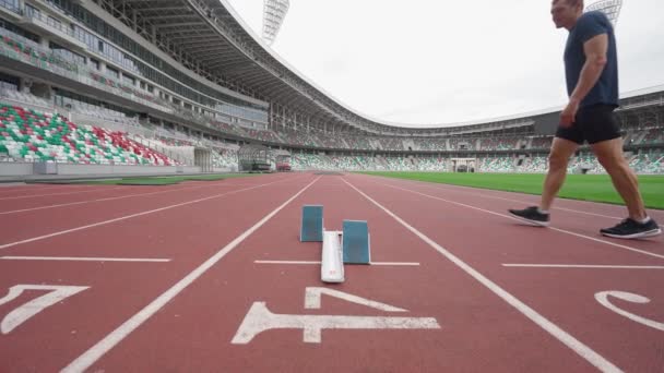 Sprinter está se preparando para o início de uma corrida de treinamento em curta distância, homem em um Estádio Olímpico, 4k câmera lenta. — Vídeo de Stock