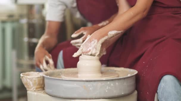 Trabalho conjunto, produção de utensílios de mesa artesanais, o jovem casal oleiro faz um jarro de barro, vista superior das mãos, artesanato. — Vídeo de Stock