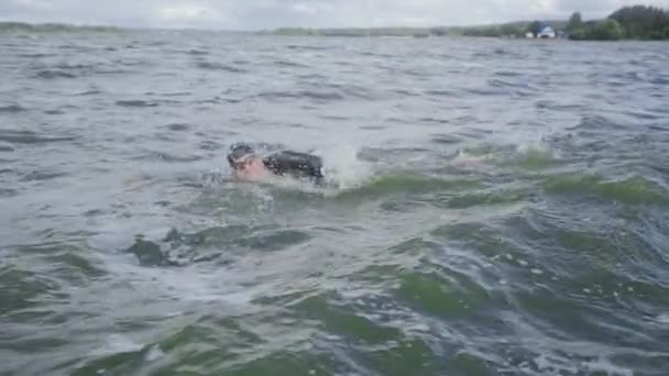 Nadador profesional, triatleta en traje de neopreno nada en aguas abiertas, un atleta entrena antes de una competición de triatlón, 4k super cámara lenta. — Vídeos de Stock