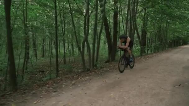 남자 트라이애슬론 선수는 자전거를 타고, 프로 사이클 선수는 숲 속 도로를 달리고, 대회와 지구력 훈련을 준비하고 , 4k 매우 느린 동작. — 비디오