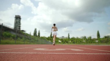 Sağlık, sabah koşusu, sportif bir kadın güneşli bir günde stadyumda koşar, arka manzara, profesyonel koşucu yarı maraton günlük antrenman.