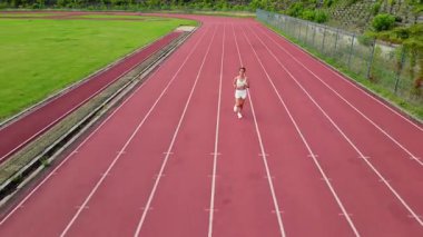 Motivasyon, sabah koşusu manzarası, sportif kadın güneşli bir günde stadyumda koşuyor, günlük antrenman yapıyor, ileri gidiyor..