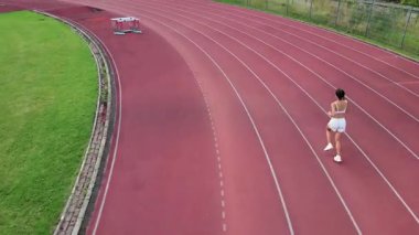 Motivasyon, sabah manzarası, sportif kadın güneşli bir günde stadyum pistinde koşuyor, günlük koşucu hava manzarası, ileri doğru gidiyor..