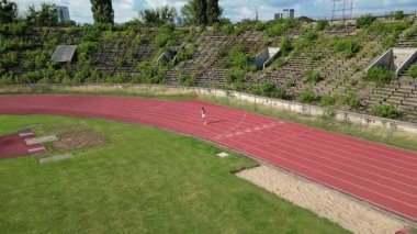 Varşova, Polonya - 18 Temmuz 2025: Sabah koşusu, güneşli bir günde bir stadyumda koşan sporcu kadın, günlük antrenman yarı maratonu, motivasyon.