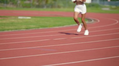 Yavaş çekim sabah koşusu, güneşli bir günde stadyumda koşan sporcu kadın günlük antrenman, başarı, motivasyon..