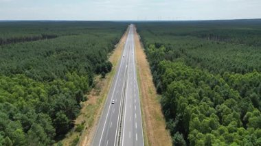 Highway, green energy, wind turbines on the horizon produce energy in the forest near the road, highway view, power extraction, alternative energy sources, wind force.
