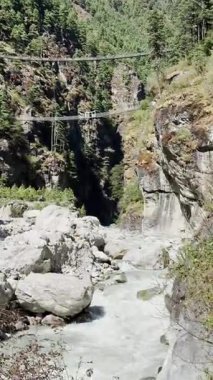 Nehir geçişi, UGC, su akıntısı manzarası ve güneşli bir dağ vadisi, asma köprüler, Himalaya dağ sırasının eteklerindeki nehir, yeşil orman.