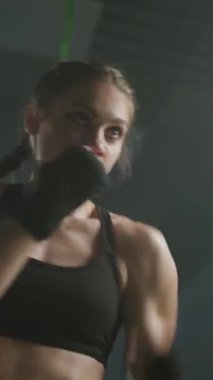 Profesyonel kadın boksör yumruklarını yener ve eğitir, boks salonunda sıkı antrenman yapar, kadın hızlı ve dikey video çeker..