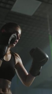 Profesyonel kadın boksör kum torbasını yener ve yumruklarını eğitir. Spor salonunda sıkı antrenman yapar. Kadın hızlı ve dikey video çeker..