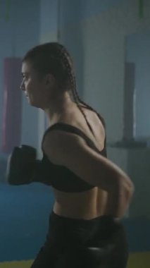 Profesyonel boksör yumruklarını yener ve eğitir, boks salonunda sıkı antrenman yapar, kadın hızlı, yavaş çekimde dikey video çeker..