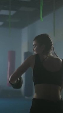 Profesyonel boksör yumruklarını yener ve eğitir, boks salonunda sıkı antrenman yapar, kadın hızlı ve dikey video çeker..