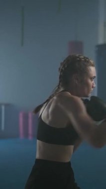 Profesyonel boksör yumruklarını yener ve eğitir, boks salonunda sıkı antrenman yapar, kadın hızlı ve dikey video çeker..
