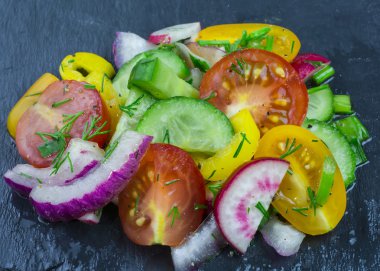 Dikey siyah taş tabakta sebze salatası