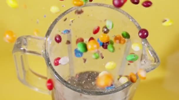 Candy explosie op gele studio achtergrond in de blender in slow motion — Stockvideo