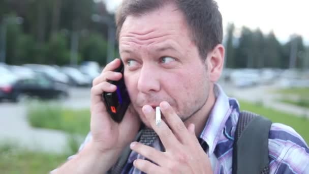Hombre nervioso fumando y hablando por teléfono celular — Vídeo de stock