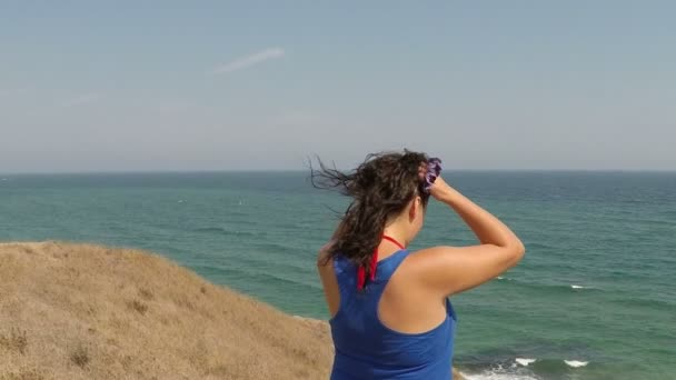 Piękna młoda kobieta dmuchanie włosów na plaży — Wideo stockowe