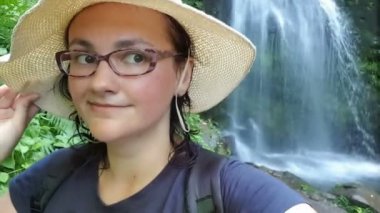 Genç ve güzel bayan turist yürüyüşçüsü yorgun ve terli bir şekilde dağlarda selfie çekiyor.