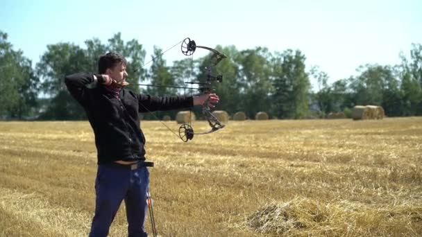 Bågskytte sport man skjuter från en båge utomhus i fält — Stockvideo
