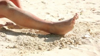 Sahilde kum ile kadın bacaklarını kullan
