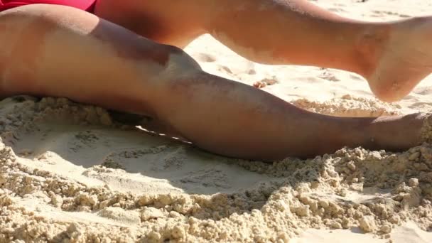 Vrouwelijke benen spelen met zand op het strand — Stockvideo