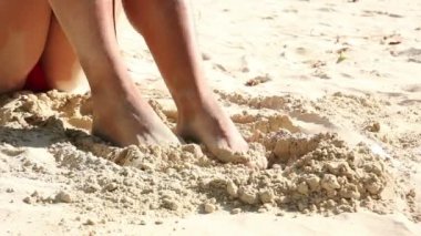 Sahilde kum ile kadın bacaklarını kullan