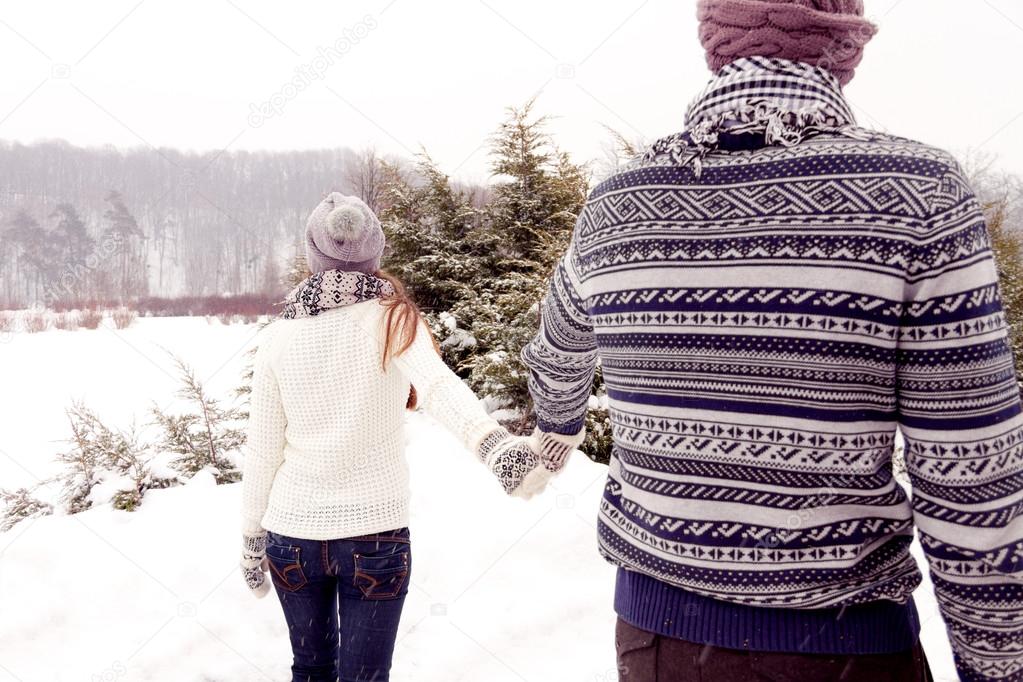 Happy couple in love walking away in park in winter