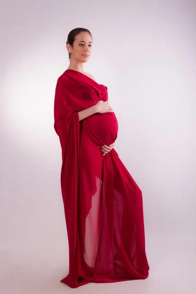 Donna incinta nei tessuti rossi — Foto Stock