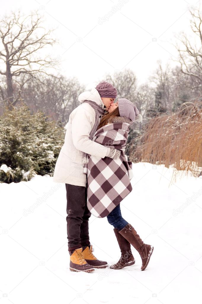 Happy couple in love kissing in park in winter