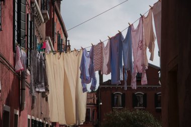 Bir kanala bakan tipik Venedik evleri. Kıyafetleri bir evden diğerine sarkıyor.