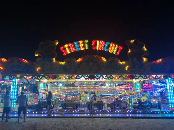 Amusement park inside the exhibition. People have fun at night. Low shutter speed and trail of lights. — Stock Photo, Image