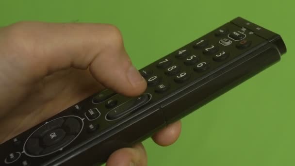 Mão masculina mudando canais com controle remoto em uma tela verde. Tiro lateral — Vídeo de Stock