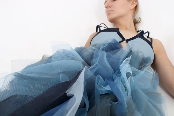 Manken bir korse ve kabarık bir tül eteğin içinde yatıyor. Bir sürü mavi tül topları, ağırlıksız, hafif, sakin