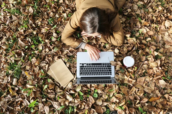 Laptop ve defter ile park içinde yatan genç güzel kadın