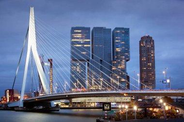 Rotterdam, Hollanda - 15 Eylül 2021: Rotterdam 'daki Erasmus Köprüsü' nün kentsel alacakaranlık manzarası ve mimarı Rem Koolhaas 'ın De Rotterdam binası
