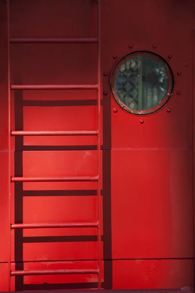 Patrijspoort en ladder op een rode schip — Stockfoto