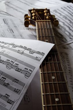 Gitar boyun, gerilmiş gitar telleri ve müzik notaları. Harika müzik parçaları ve üzerinde güzel müzik çalabileceğin bir enstrüman..