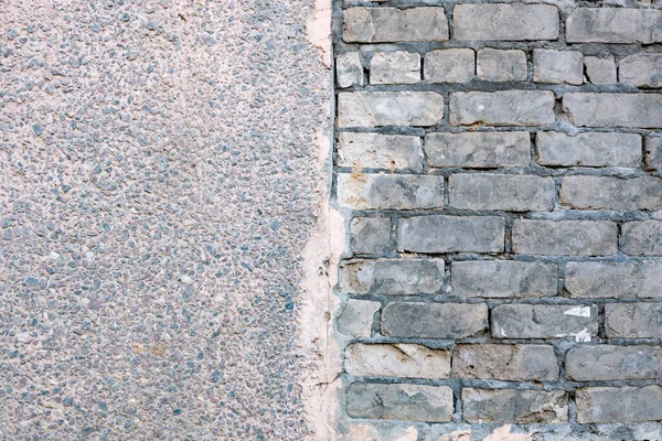 Tuğla duvar dokusu fotoğrafı, gri silikat tuğladan yapılmış, harç akışı ve düz olmayan tuğla işi. Aynı duvardaki iki dokunun fotoğrafı. Duvarın yarısı betondan, duvarın yarısı tuğladan yapılmış..