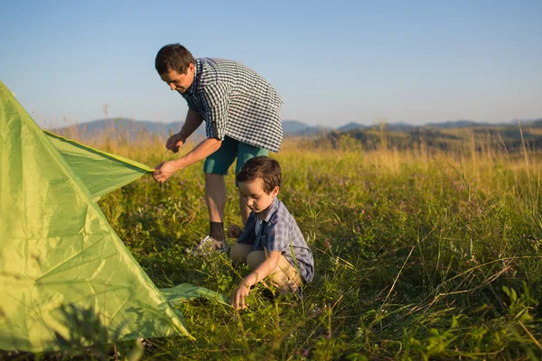 Отец с сыном вместе поставили палатку. — стоковое фото
