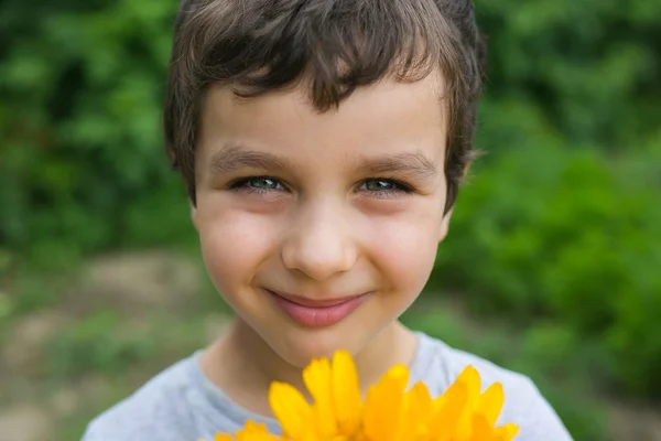 노란색 꽃과 함께 귀여운 미소 소년의 초상화 — 스톡 사진