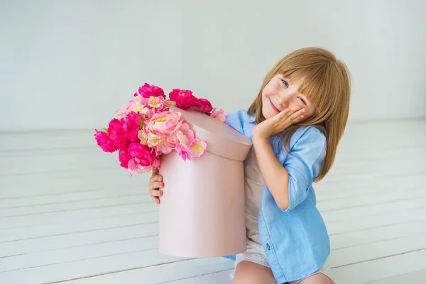 Vidám kislány rendelkezik egy doboz egy virág, és, hogy szeme — Stock Fotó