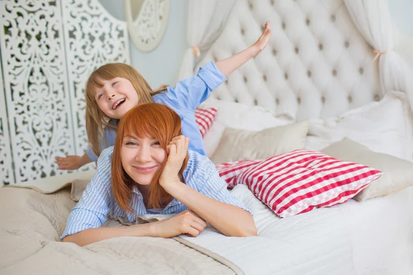 Mother plays with her little daughter on a bed (flying)