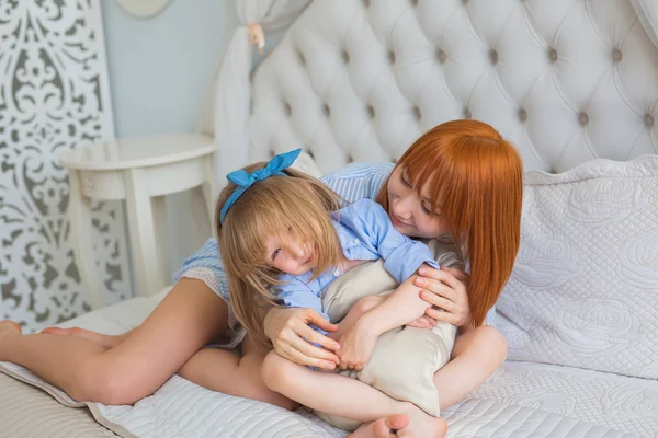 Mother hugs her little daughter on a bed in the morning — Stock Photo, Image