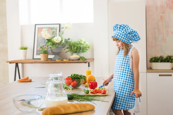 Bella bambina in abiti da cuoco pensa su una cucina — Foto Stock