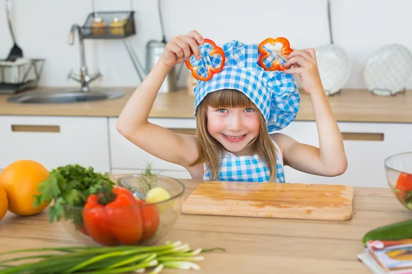 Ritratto di una graziosa bambina in abiti da cuoca con fette di peperone su una testa — Foto Stock