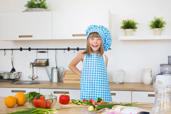 Bella bambina in abiti da cuoco sorride su una cucina — Foto Stock