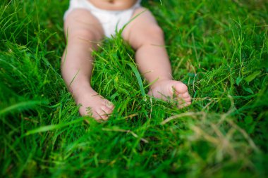 A legs of a human baby at a diaper on a grass clipart